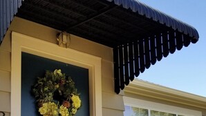 A house with a dark blue front door, a decorative wreath, and a small porch with a railing. - Charming and Convenient! No cleaning fee. Sleeps 6. (Anaconda)