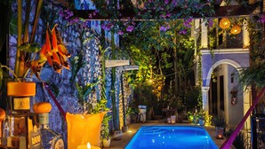Un área de piscina con hamaca, velas y plantas.