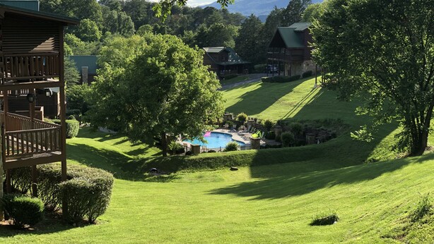 Et resort med pool, frodige grønne arealer og et bjerg i baggrunden.