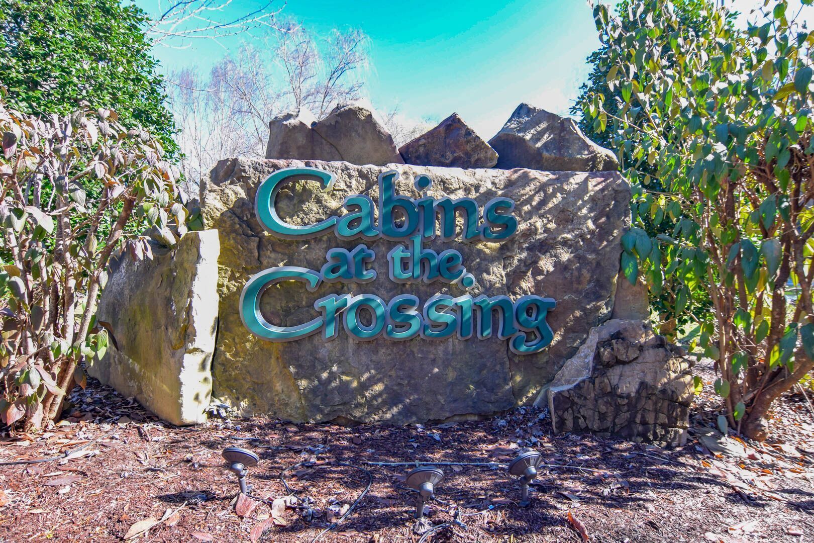 Ein großer Felsen, in den der Schriftzug „Cabins at the Crossing“ geritzt ist.
