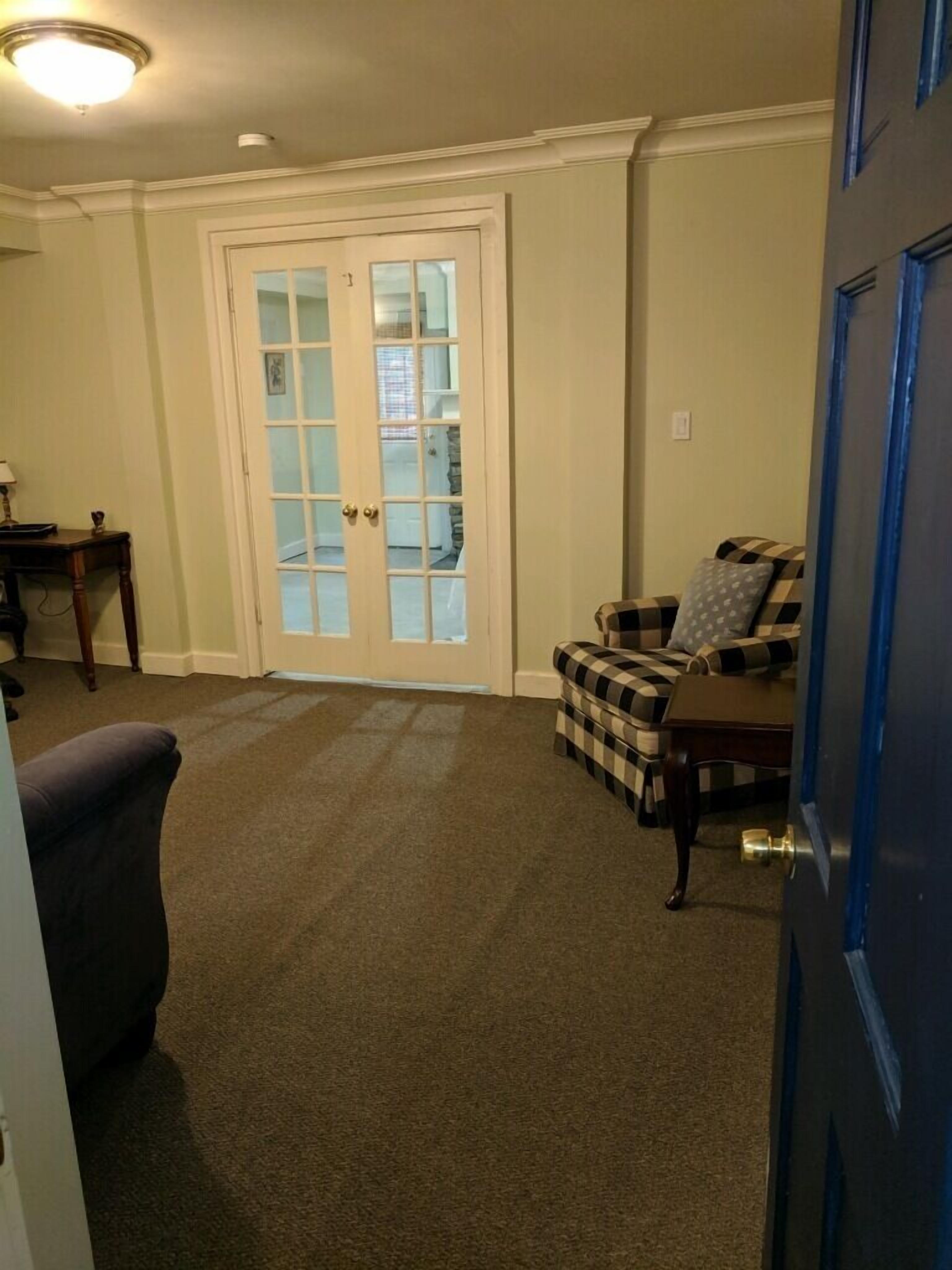 En stue med en ternet sofa, et lille bord og en dør med glasruder.