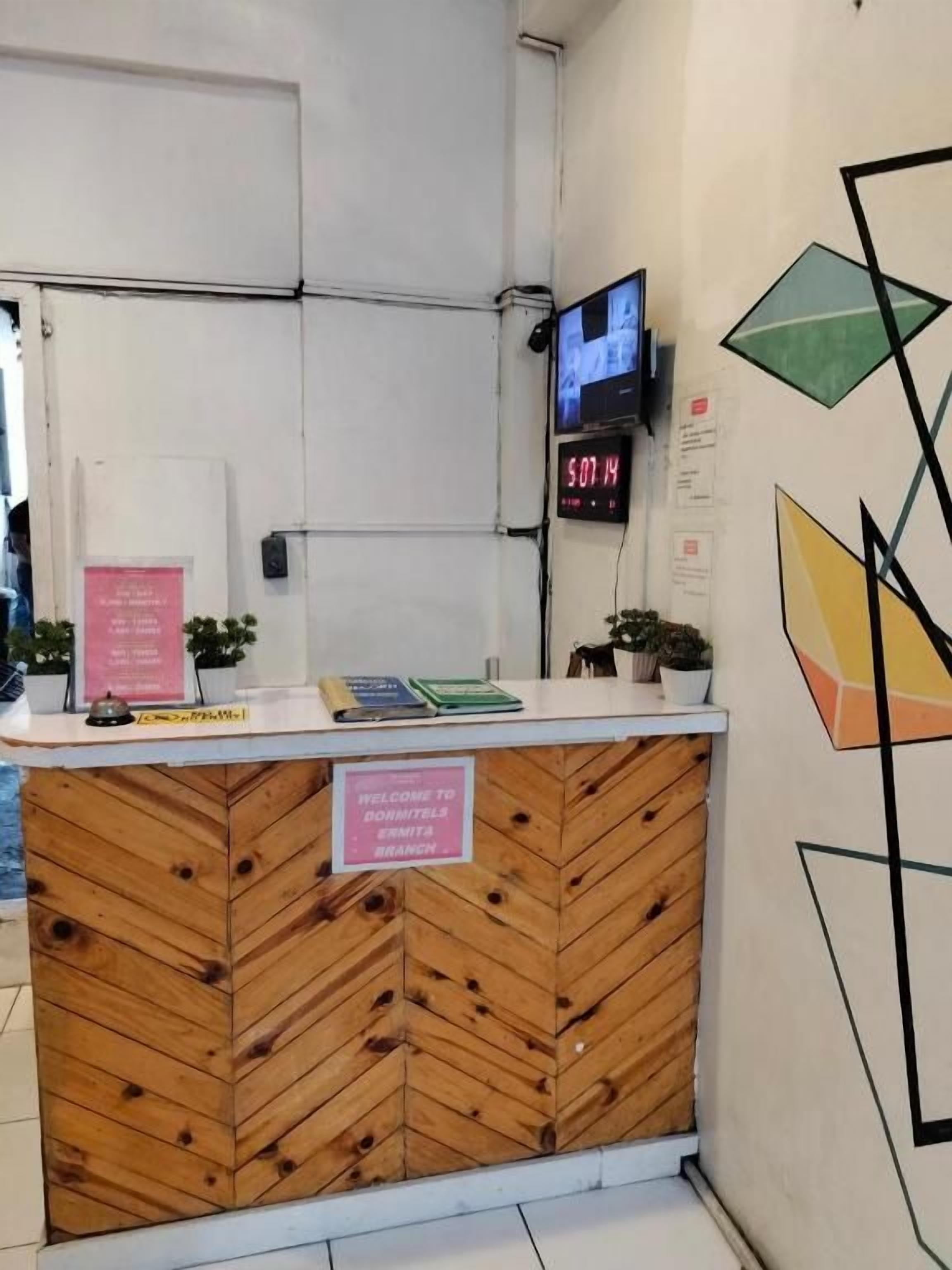 A reception desk with a digital clock, a sign indicating the branch, and a wall with geometric art.