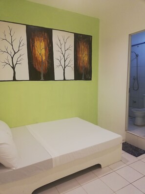 A room with a bed, a green wall, and three paintings of trees. - Dormitels.ph Ermita (Manila)