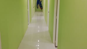 A long, narrow hallway with green walls and white floors.