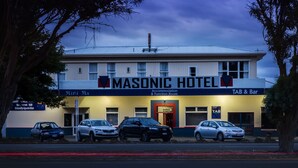 The Masonic Hotel with a signboard, a TAB & Bar, and several parked cars.