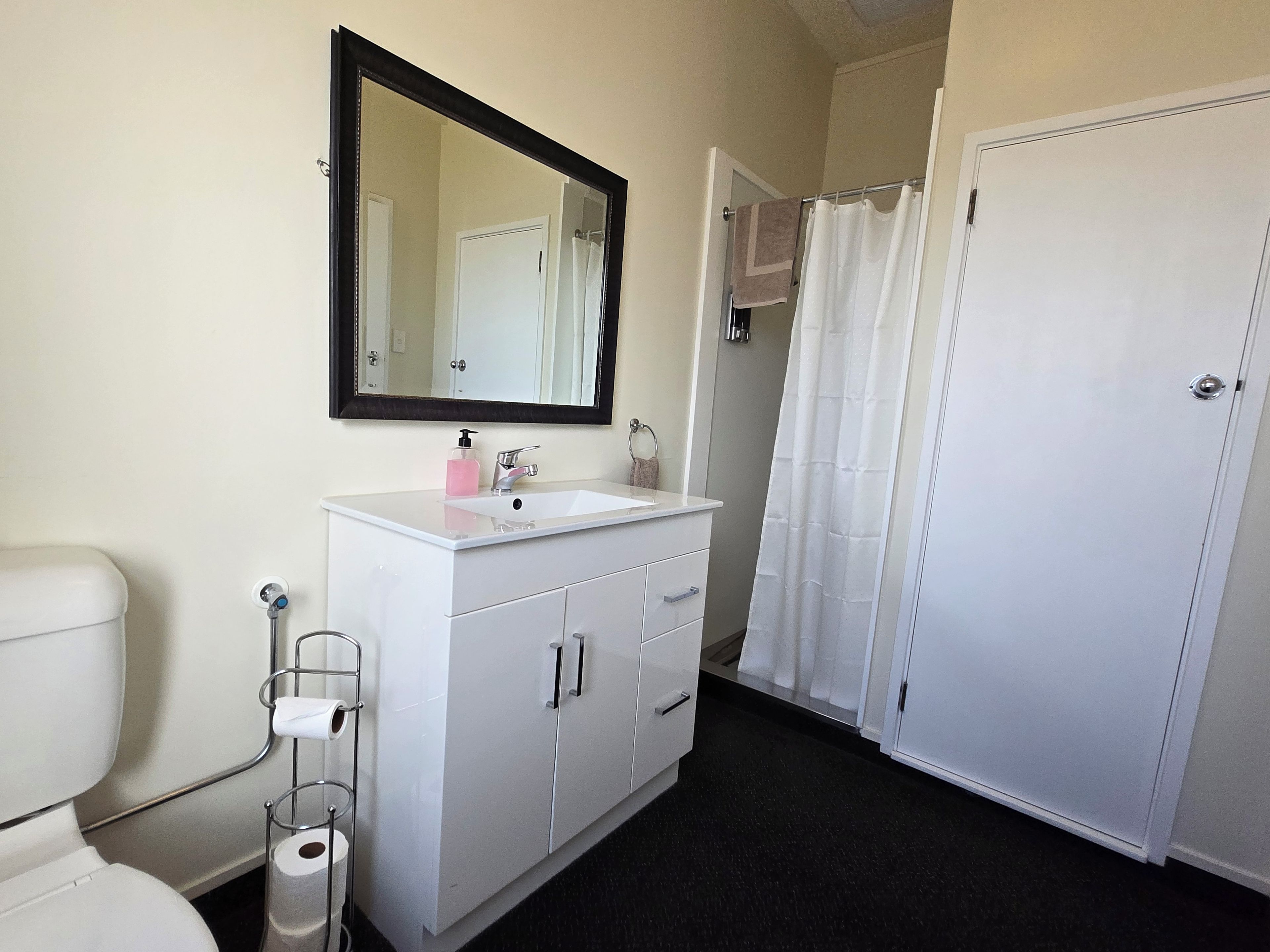 A bathroom with a white sink, mirror, toilet, and a shower curtain.