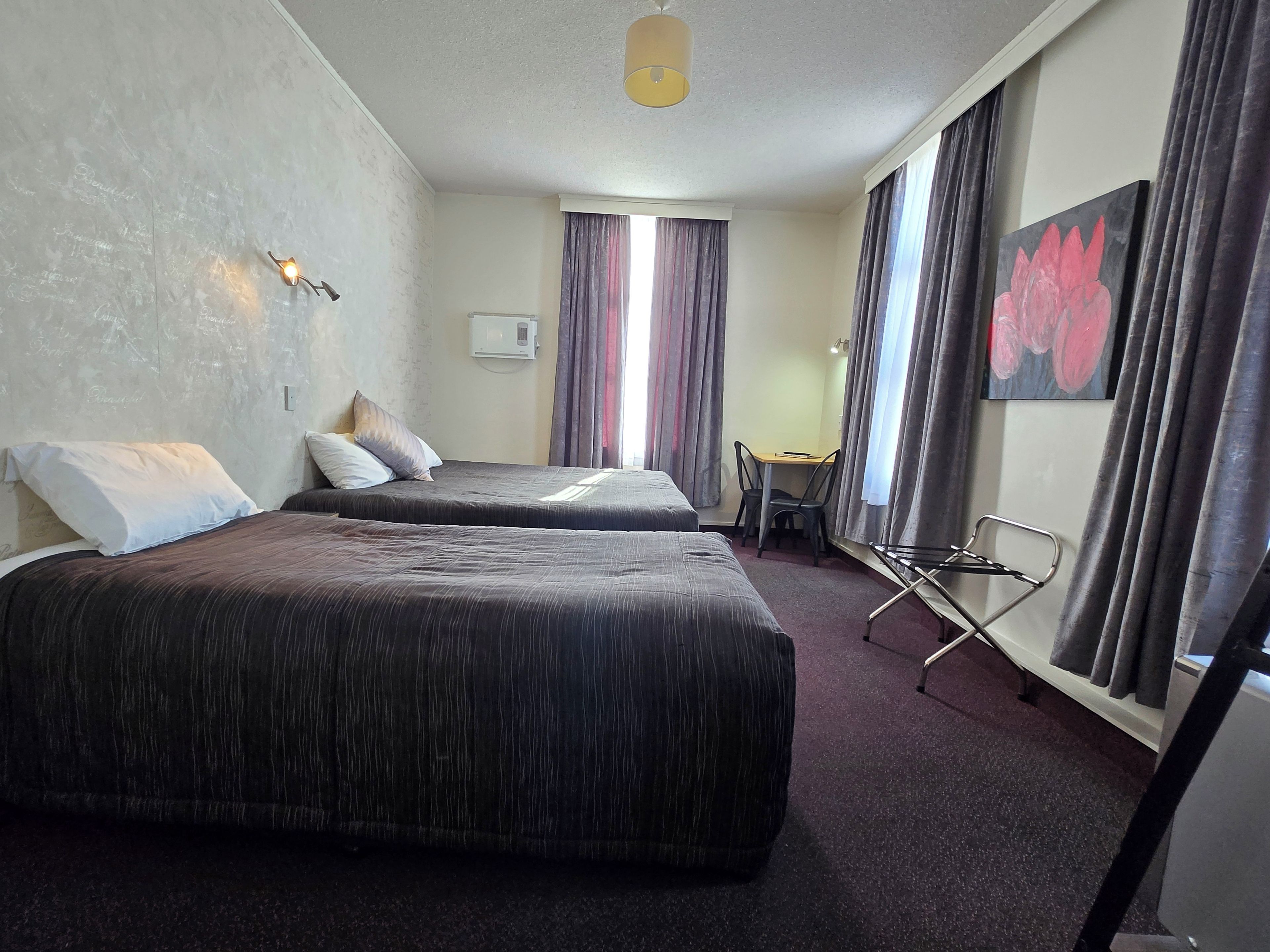 A hotel room with two beds, a desk, and a chair.