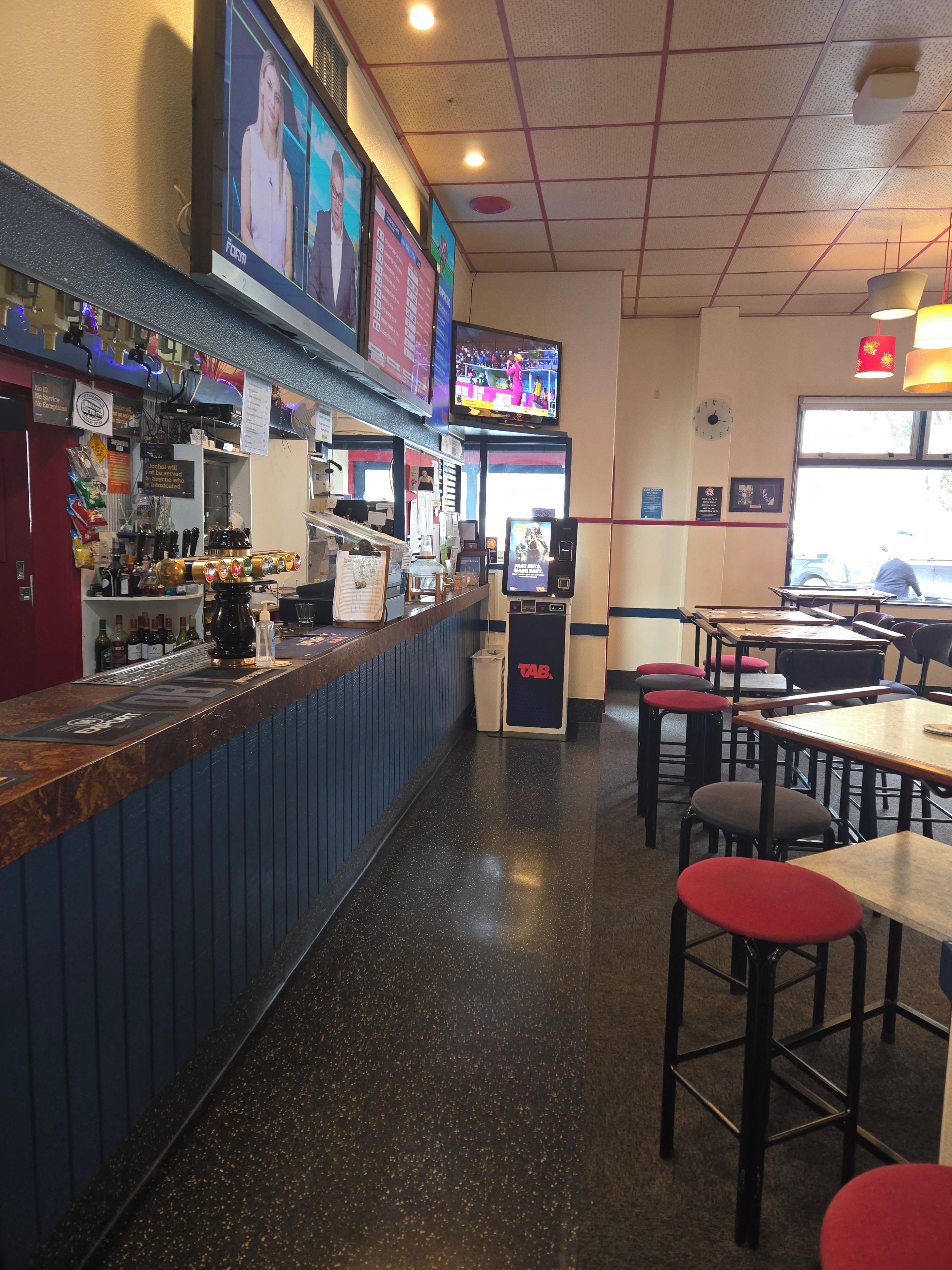 A restaurant interior with a bar area, tables, and chairs.