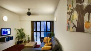 A modern living room with a sofa, a flat-screen TV, and potted plants.