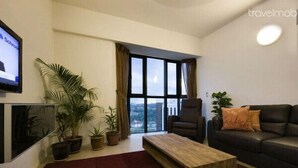 A modern living room with a large window, a sofa, a coffee table, and several potted plants.