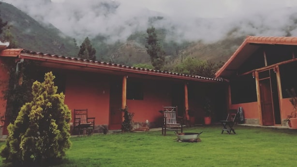 A red-roofed building with a grassy courtyard, a small tree, and a chair.