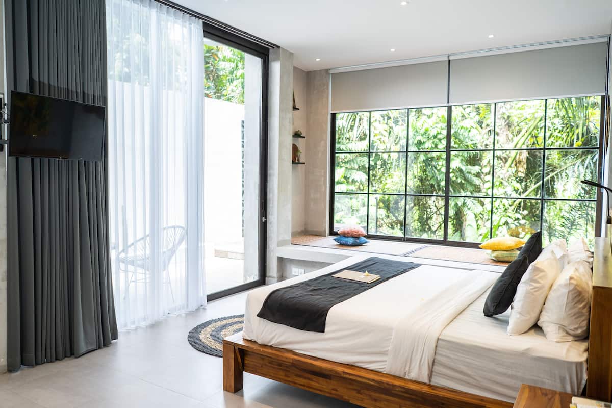 Une chambre moderne avec une grande fenêtre, un lit et un téléviseur.