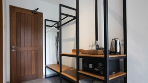 Une pièce avec une porte en bois, une étagère en métal sur laquelle se trouve un four à micro-ondes, et un petit réfrigérateur.