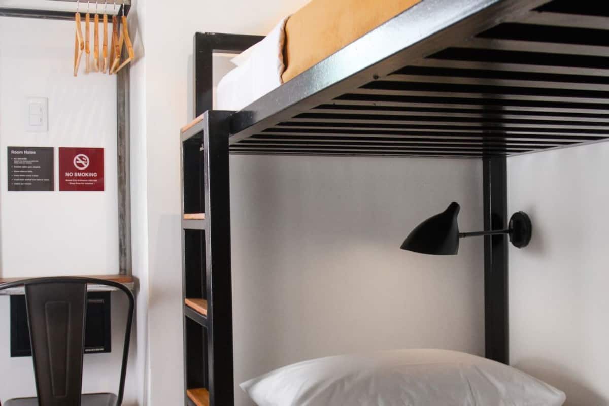A bunk bed with a desk and chair, a no smoking sign, and a room number sign.