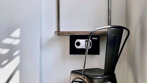 A modern room with a black metal chair, a red accent wall, and a wooden clothes rack. - Gomez House (Makati)