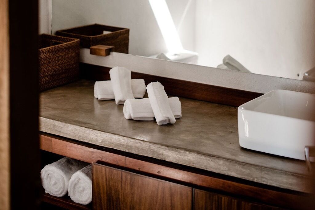 A bathroom counter with neatly folded towels, a mirror, and a white container.