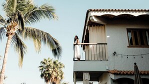 Un edificio di due piani con un balcone, una palma e luci decorative.