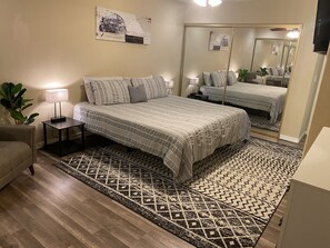 Ein Schlafzimmer mit einem großen Bett, Nachttischen, einem Spiegel und einem gemusterten Teppich.