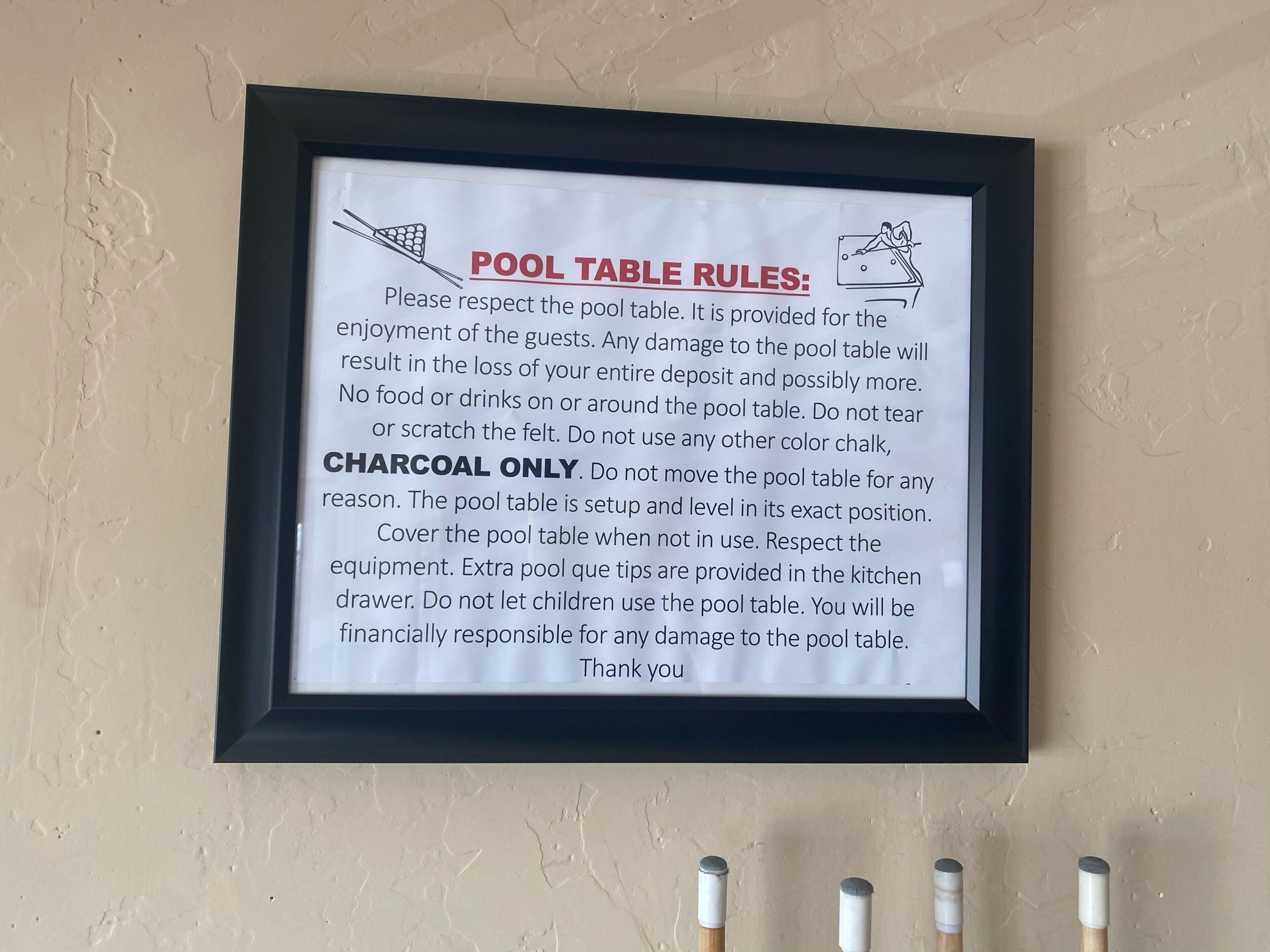 Un cartel con las reglas de la mesa de billar enmarcado en una pared.