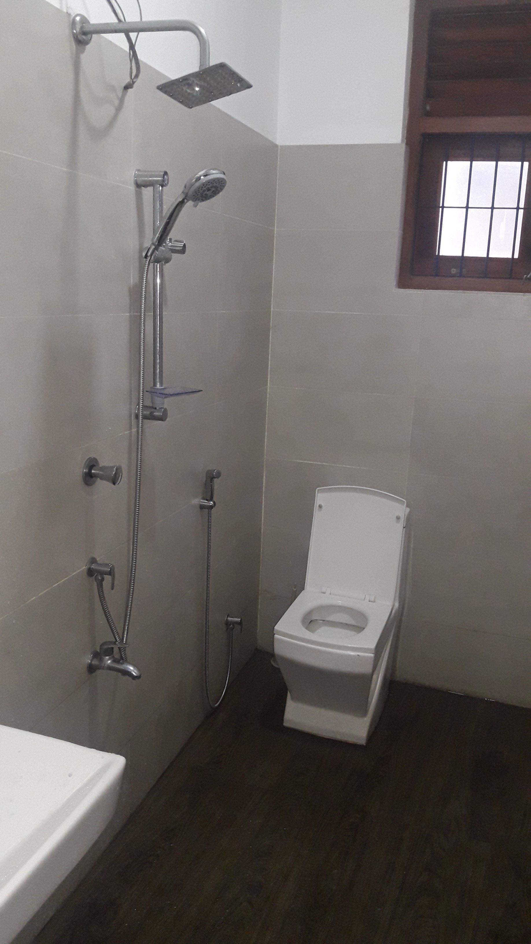 Une salle de bain avec une douche, des toilettes et une fenêtre.
