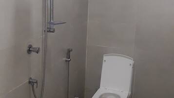 Une salle de bain avec une douche, des toilettes et une fenêtre.