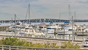 A marina with multiple boats docked, a bridge in the background, and a road in the foreground. - BSL Living - Across from Pickleball Courts, Splash Pad and Park - Permit #BSL140 (Bay St Louis)