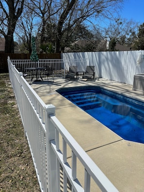Relax by the pool surrounded by a serene lawn and a wooden deck.