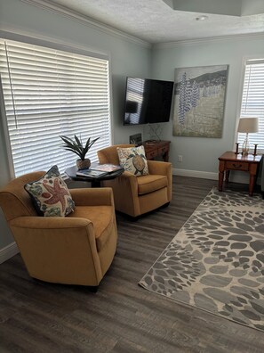 Relax in a comfortable living room with a large flat-screen TV, two armchairs, and a coffee table.