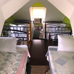 A dormitory-style room with bunk beds, a small window, and a heater.