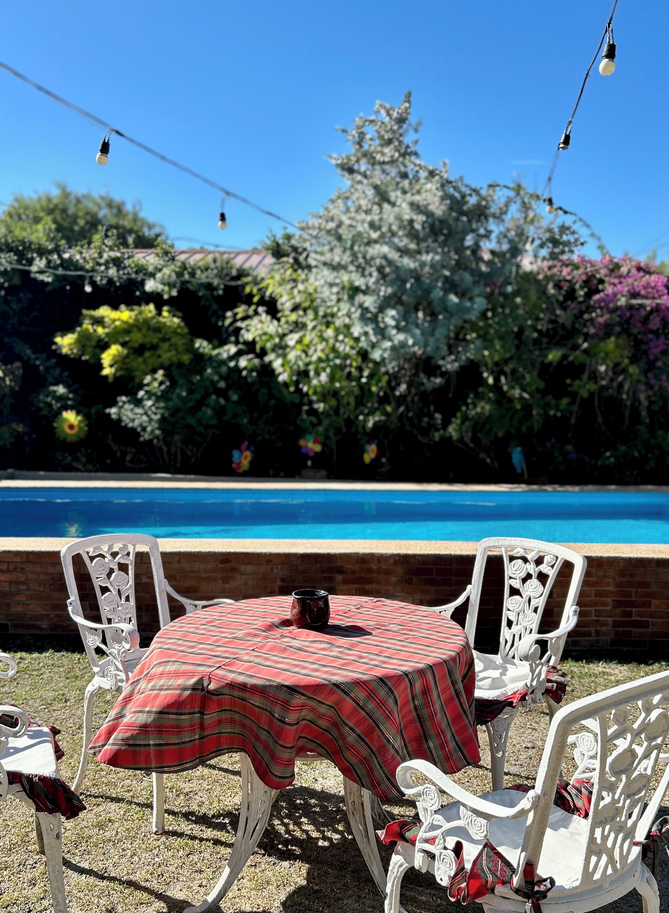 Un área de estar al aire libre con una piscina al fondo.