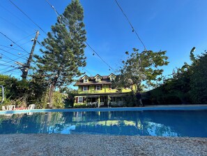 A two-story house with a swimming pool in front.