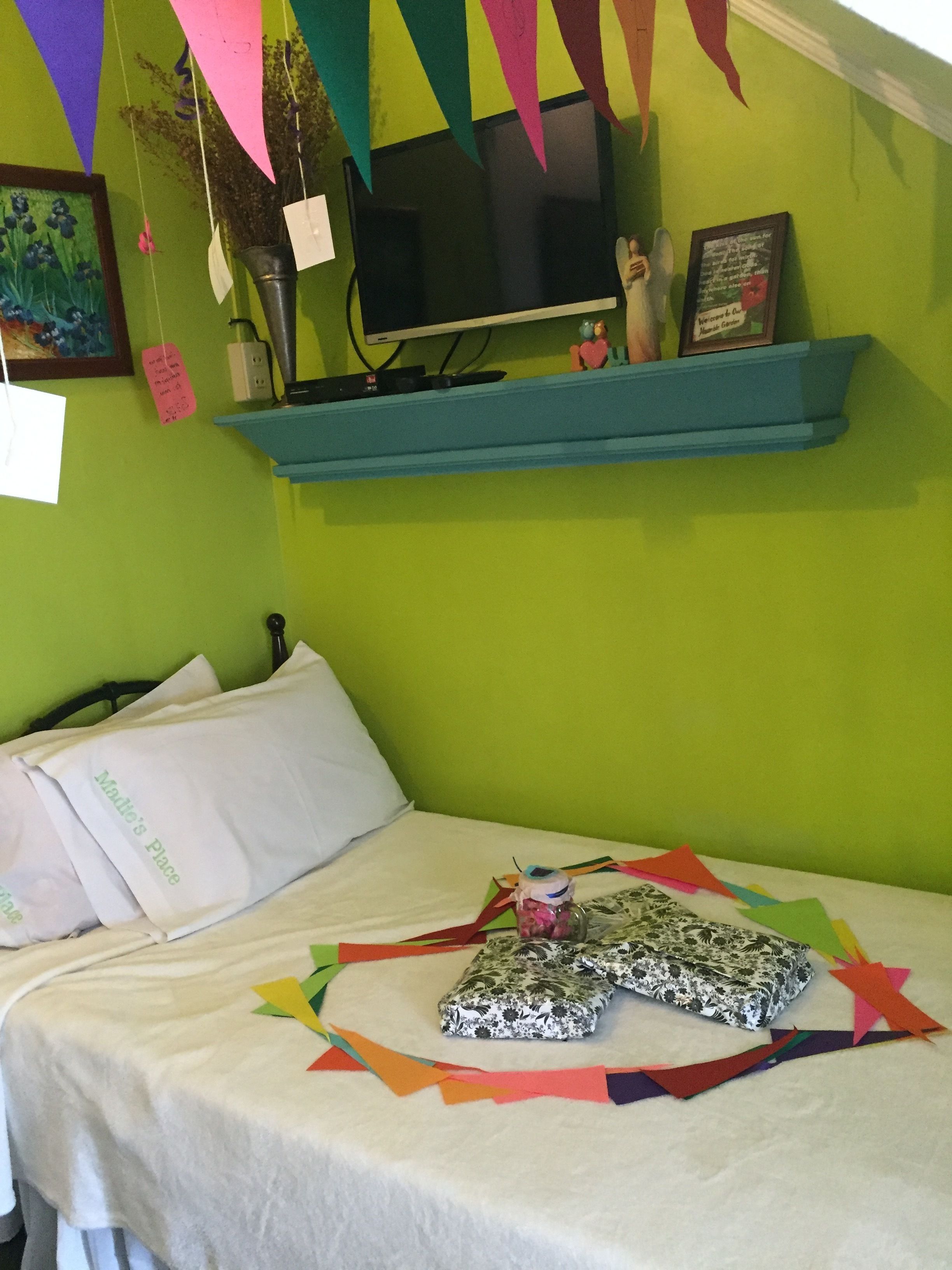 A bed with white bedding, a floral-patterned pillow, and a colorful paper decoration.