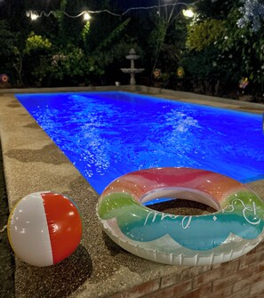 A swimming pool with a colorful inflatable ring and a beach ball.