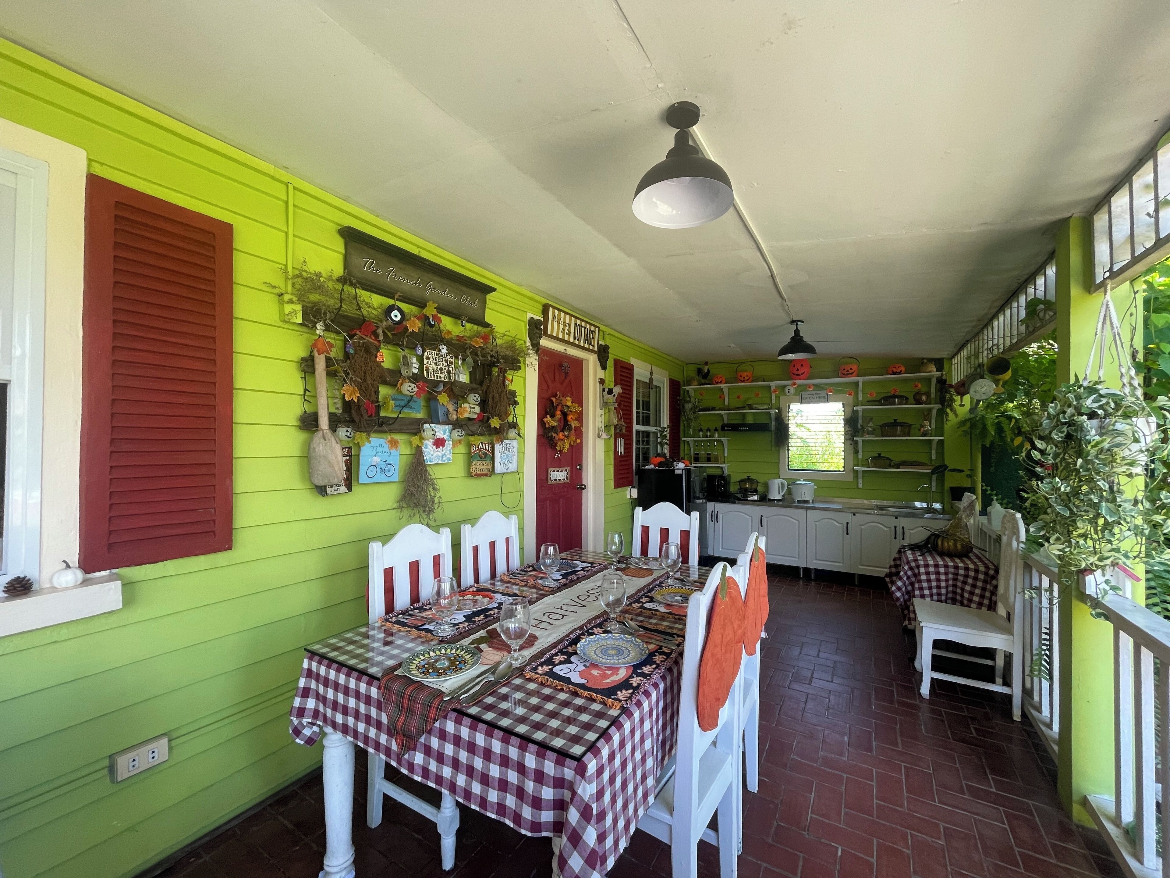 A dining area with a table set for four, white chairs, and a red and white checkered tablecloth.