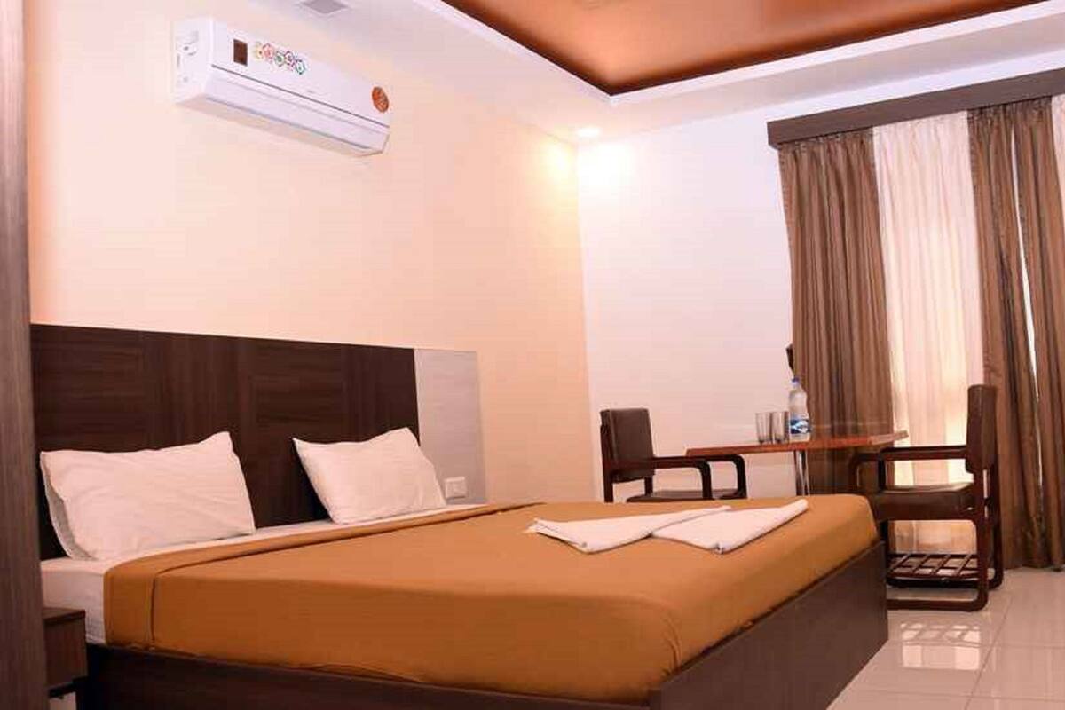 A hotel room with a bed, a desk, a chair, and a window with curtains.