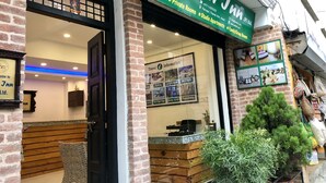 Entrada de hotel con un letrero verde, un mostrador de recepción y un cartel con información turística enmarcado.