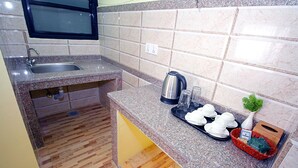 Una cocina compacta con encimera de granito, lavamanos integrado y un ventanal.