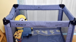 Een Graco babybedje met een gaas bovenkant en een speelgoed Minion erin.