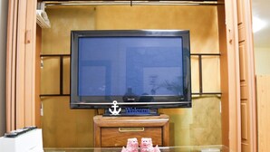 Een televisie op een houten standaard, met een welkomstbord en twee beeldjes ervoor.