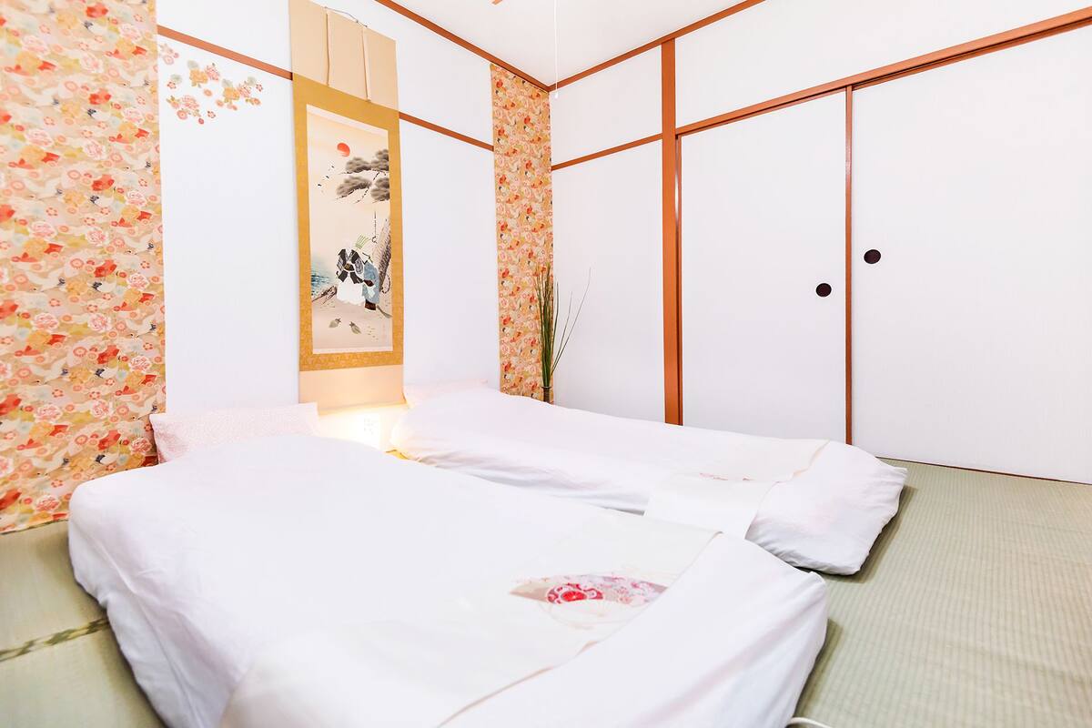 A neatly arranged bedroom with a bed, a wall-mounted shelf with a decorative item, and a wardrobe with a sliding door.