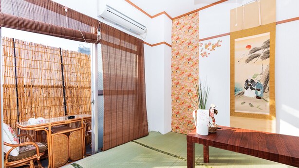 Une pièce de style japonais traditionnel, avec un sol recouvert de tatamis, une table en bois, une chaise en osier et un paravent en bambou.