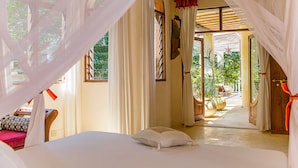 A bedroom with a bed, curtains, and a view of the outdoors. - Monkey Beach House, Beachfront, Ocean Views,  Shared Pool, Staff Provided (Diani Beach)