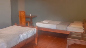 Een kamer met twee houten bedden, een klein houten tafeltje en een stoel.