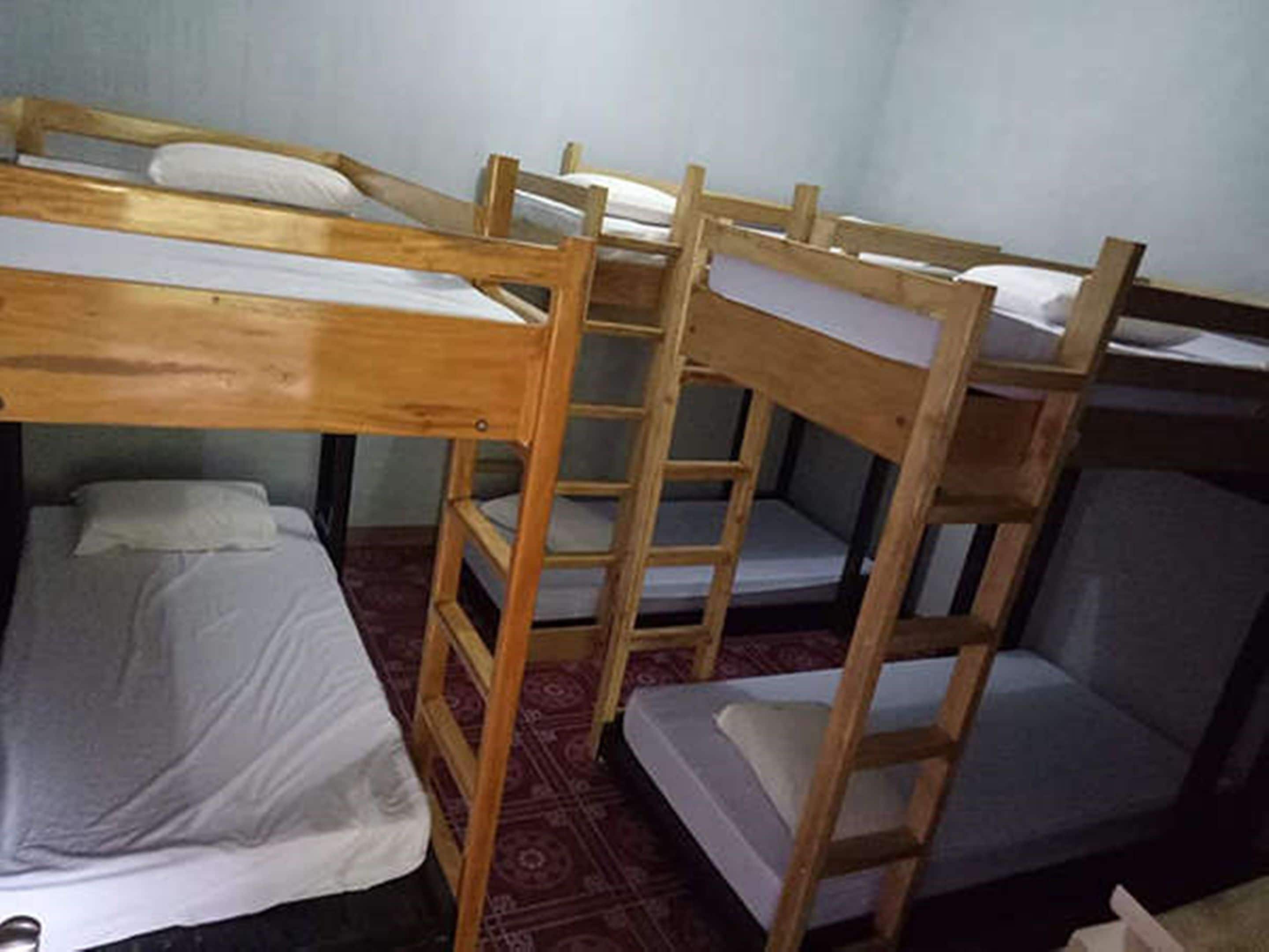 Dormitorio con literas de madera y ropa de cama blanca.