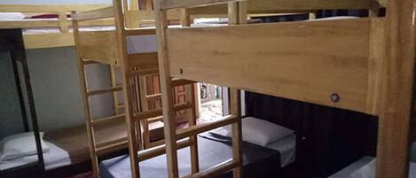Une chambre avec un lit superposé, un tapis rouge, des meubles en bois et une fenêtre avec des rideaux.