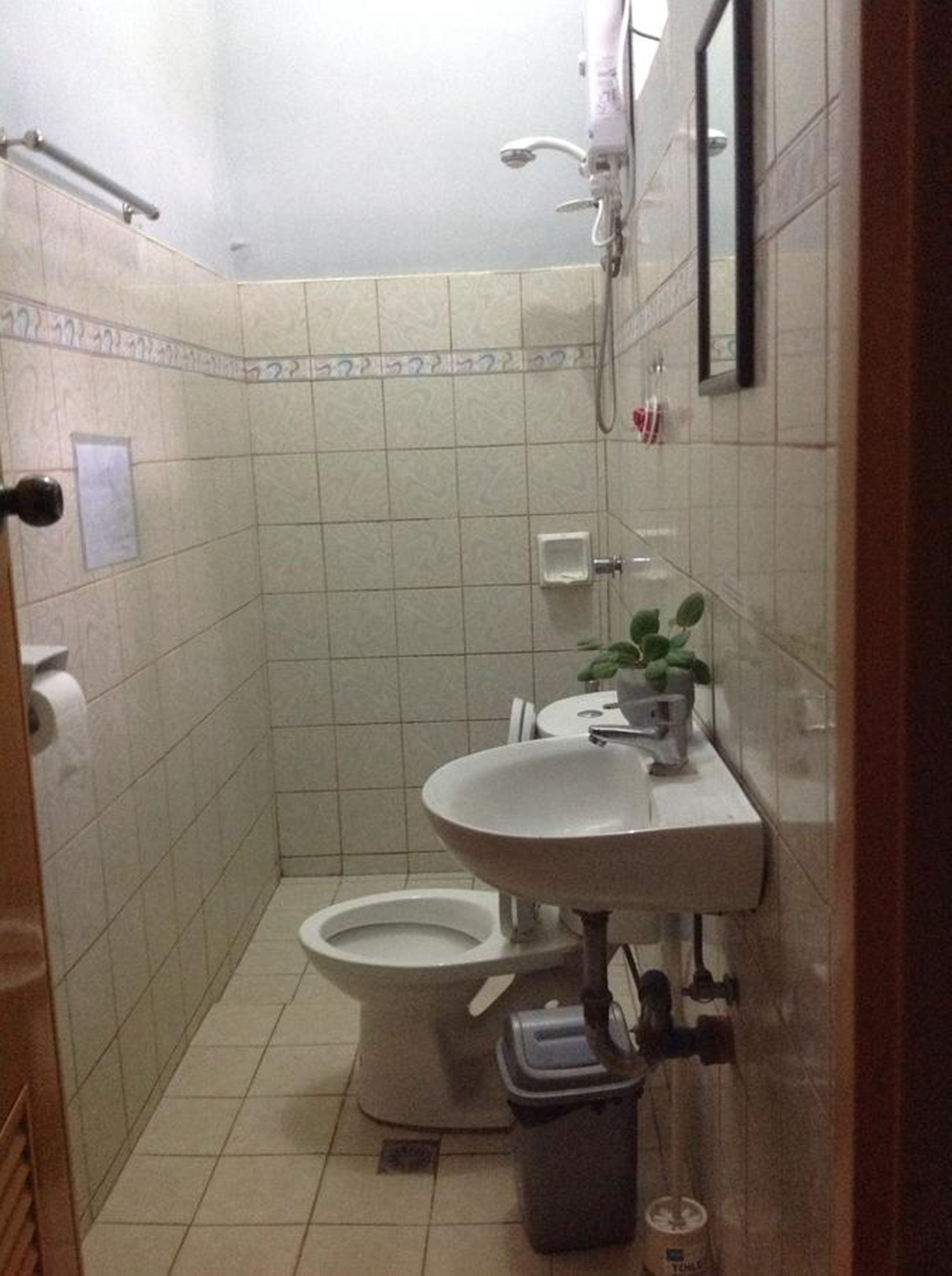 Pieni kylpyhuone, jossa on wc, pesuallas ja suihku.