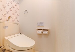 A small, clean bathroom with a toilet, a paper towel dispenser, and a toilet paper holder. - Namba Sunshine Apartment 73 (Osaka)