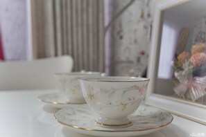 A table with two white cups with gold rims and floral designs, placed on matching saucers. - Namba Sunshine Apartment 73 (Osaka)