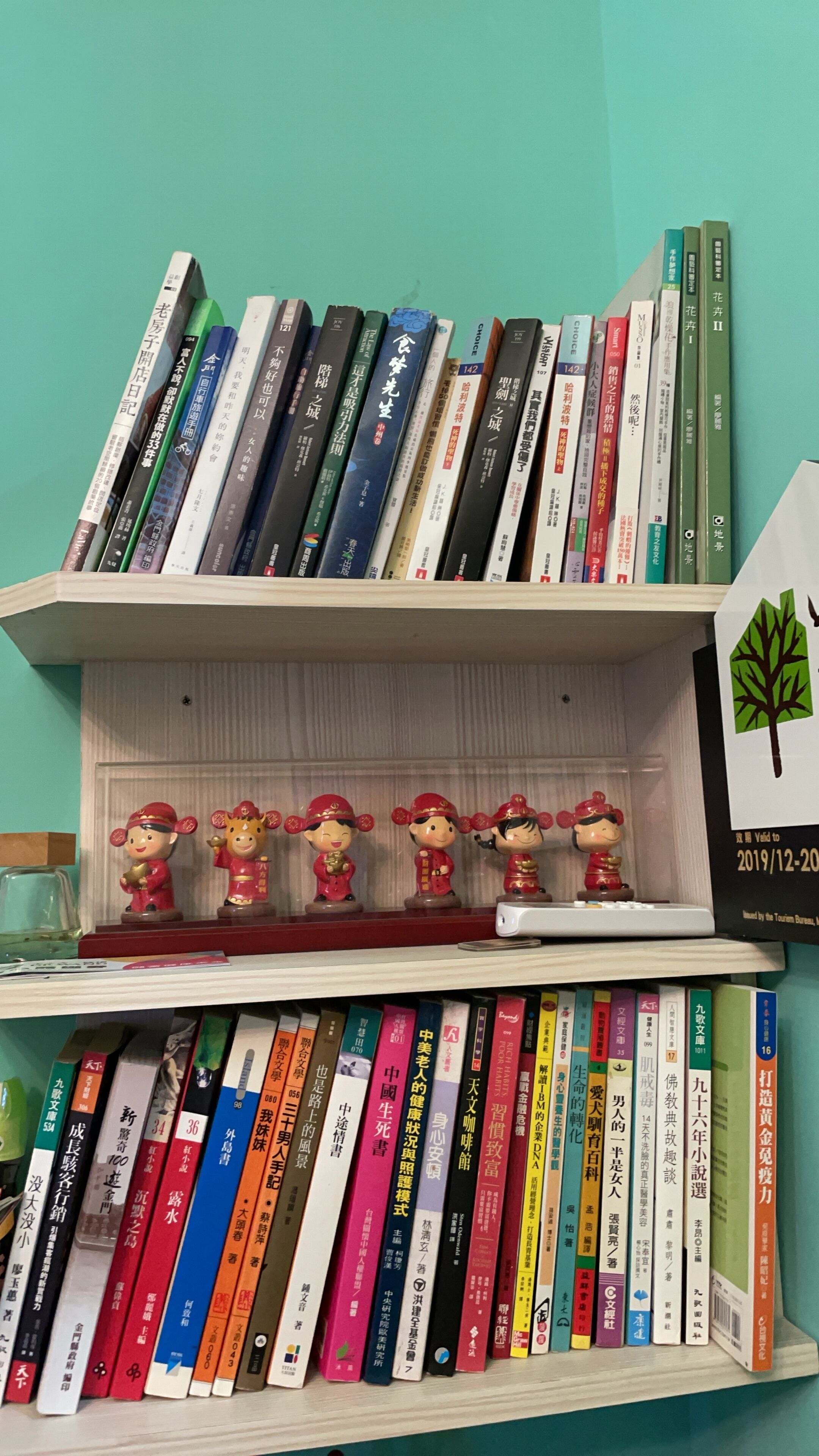 A bookshelf with various books and decorative figurines.