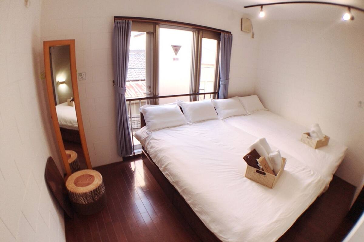 A hotel room with a large bed, a mirror, a small round table, and a window with curtains.